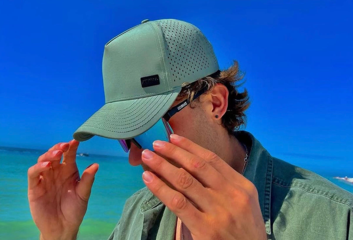 Man wearing a green Atama performance hat at the beach