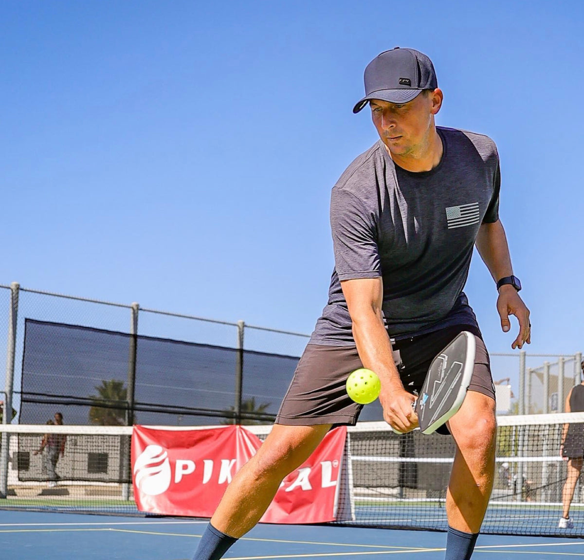 Man playing pickleball wearing a gray Atama performance hat